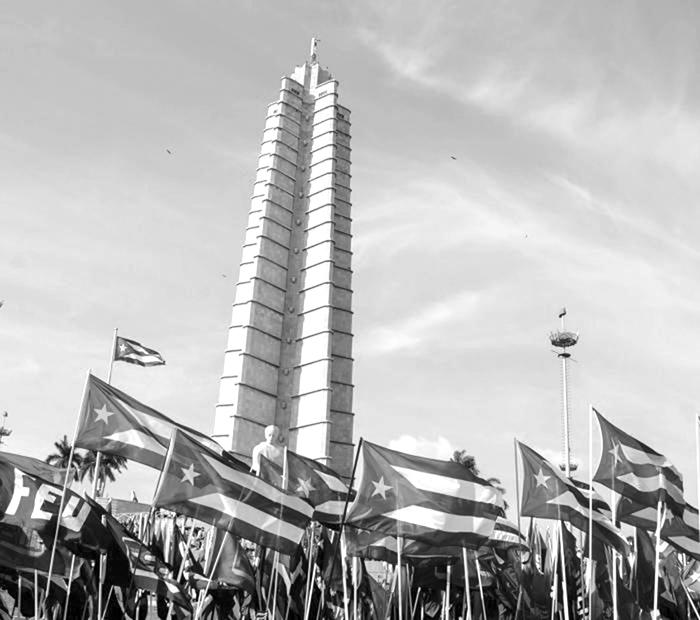 Milhares de bandeiras brancas, vermelhas e azúis passam em frente da estátua de José Martí.